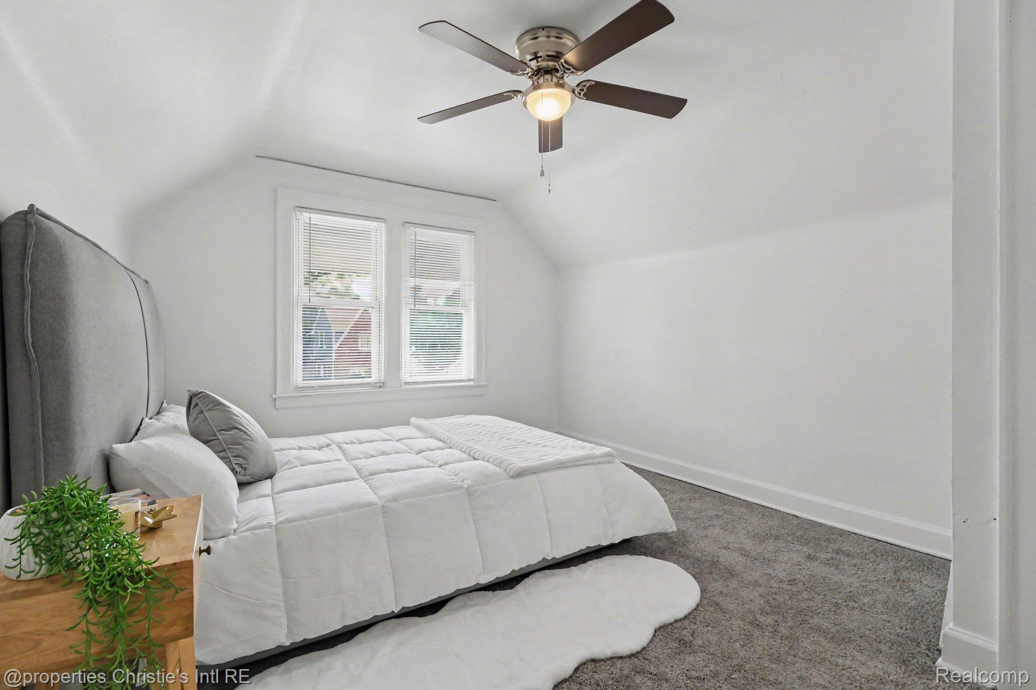 18315 Prairie Street Detroit, MI 48221 - Photo 10 of 16 Bright room featuring a sloped ceiling, two windows with blinds, a ceiling fan with integrated lighting, and gray carpet flooring