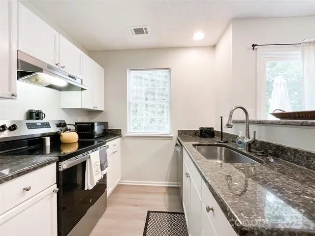 a kitchen with granite countertop a sink and a stove top oven