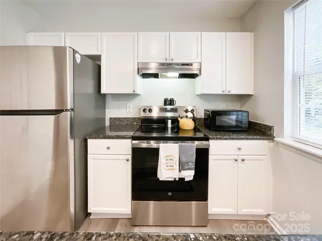 a kitchen with stainless steel appliances granite countertop a refrigerator sink and white cabinets