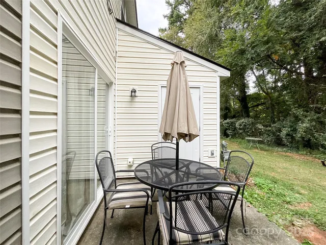 a patio with table and chairs and potted plants