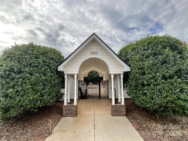a view of a house with a yard plants and large tree
