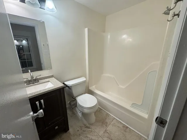 a bathroom with a granite countertop toilet sink and mirror
