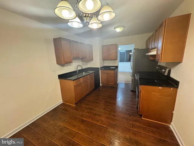 a kitchen with stainless steel appliances granite countertop a stove a refrigerator a sink a dining table and chairs with wooden floor