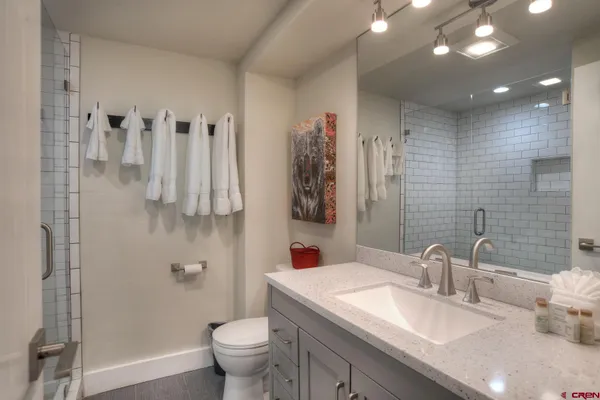 a bathroom with a granite countertop sink a toilet and a shower