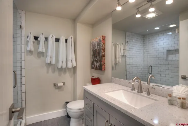 a bathroom with a granite countertop sink a toilet and a shower