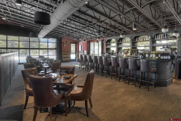 a front view of a building with lot of cars and trees