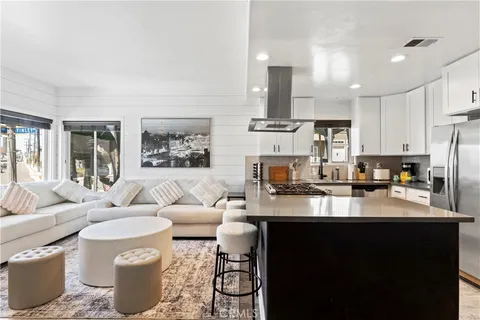 a living room with stainless steel appliances kitchen island granite countertop a stove and a sink