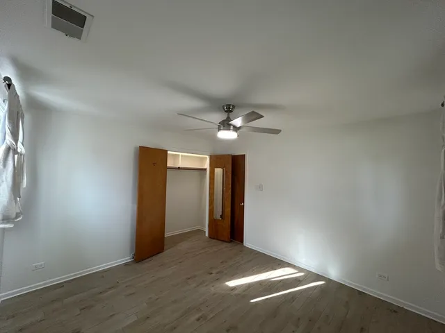 an empty room with closet and a chandelier fan
