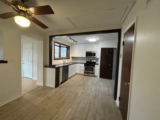 a large kitchen with cabinets wooden floor and stainless steel appliances