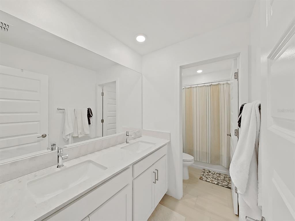 8312 Rolling Tides Drive New Port Richey, FL 34655 - Photo 37 of 49 a spacious bathroom with a double vanity sink a toilet and a mirror