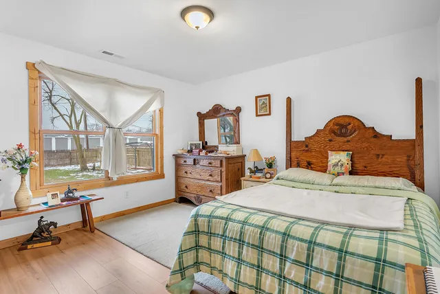 a bedroom with a bed a table and large windows