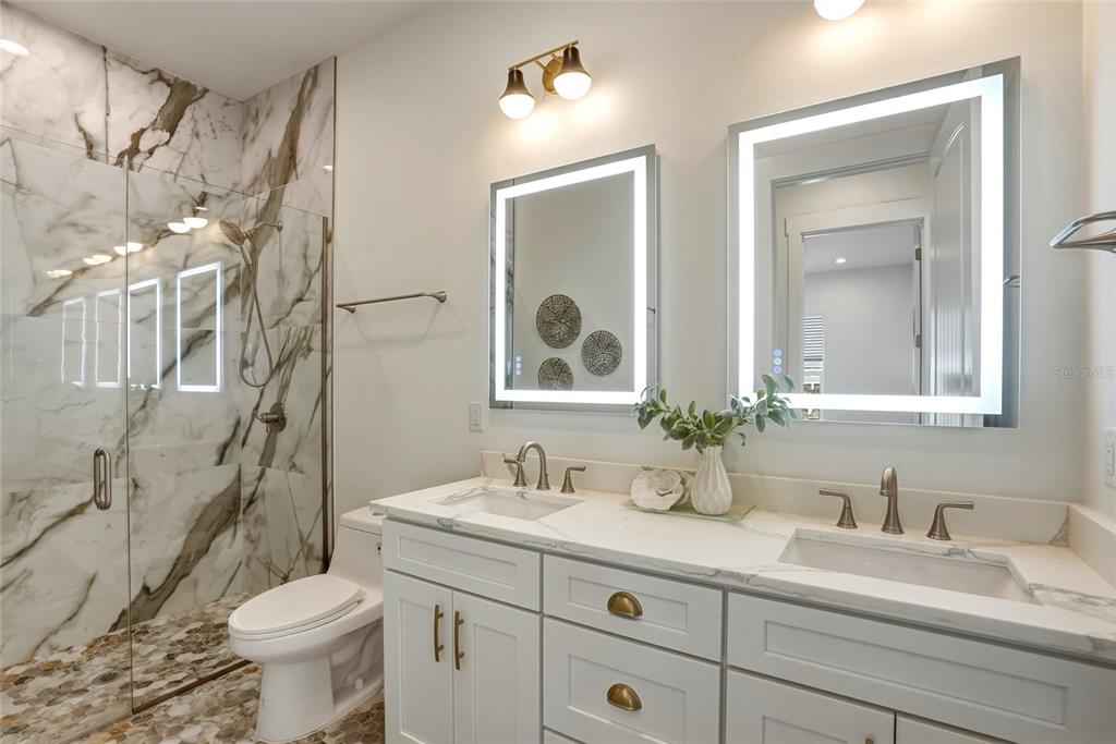 534 Crystal Drive Madeira Beach, FL 33708 - Photo 39 of 68 a bathroom with a granite countertop sink mirror vanity and toilet