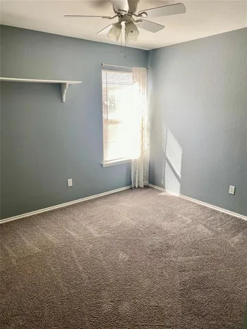 an empty room with a window and a chandelier fan