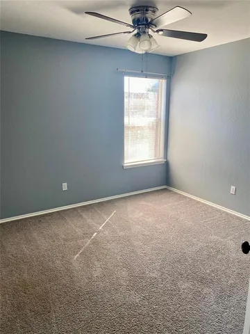 an empty room with a window and a fan