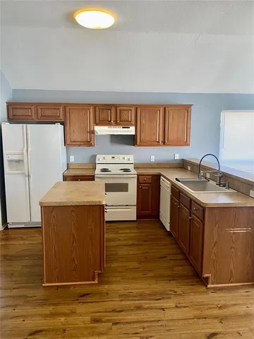 a kitchen with wooden cabinets a sink a stove and a refrigerator