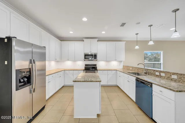 a kitchen with stainless steel appliances granite countertop a refrigerator a sink dishwasher a refrigerator and white cabinets with wooden floor