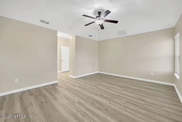 a view of an empty room with a window and wooden floor