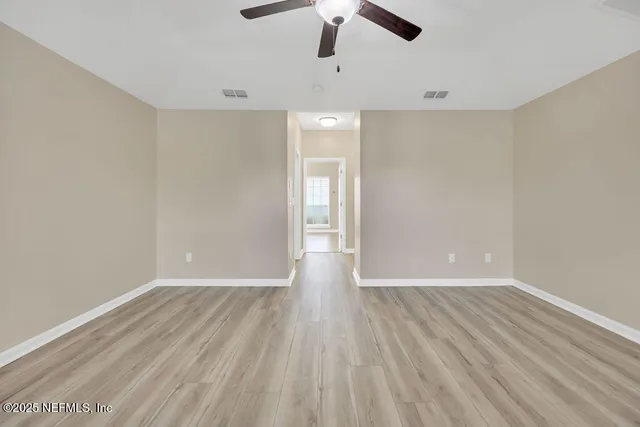 an empty room with wooden floor and ceiling fan