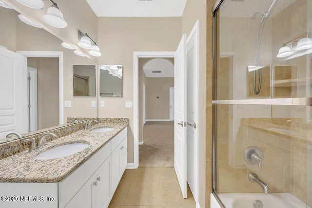 a bathroom with a granite countertop double vanity sink a mirror and a toilet