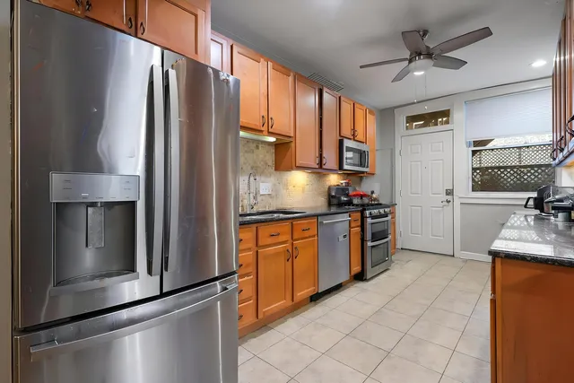 a kitchen with stainless steel appliances granite countertop a refrigerator a stove and a sink