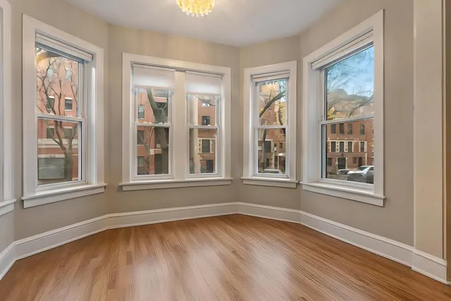 a view of an empty room with wooden floor and windows