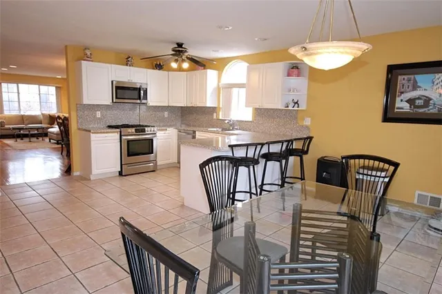 a kitchen with stainless steel appliances granite countertop a kitchen island a stove a dining table and chairs