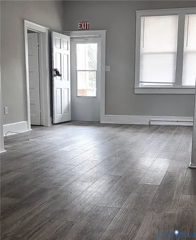an empty room with wooden floor and windows