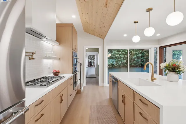 a kitchen with kitchen island a stove a sink a refrigerator and a dining table with wooden floor