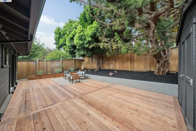 a view of backyard with table and chairs and wooden fence