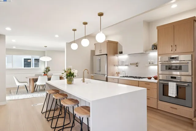 a large white kitchen with a large counter top appliances and cabinets
