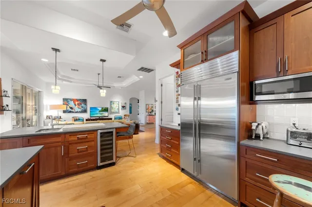 a kitchen with stainless steel appliances granite countertop a refrigerator a stove and a sink with wooden floor