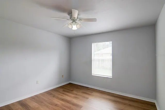 a view of an empty room with chandelier fan and a window