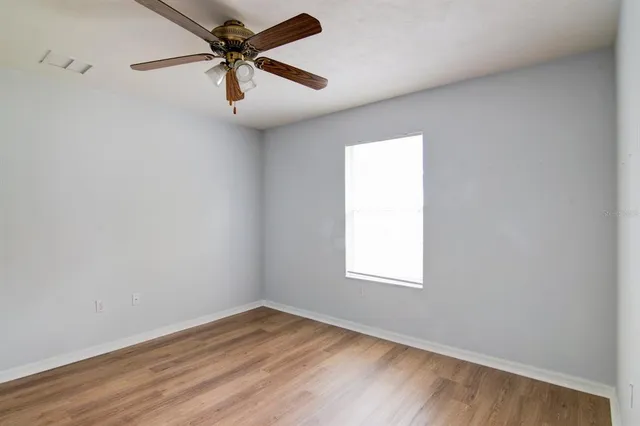 an empty room with a window and a fan