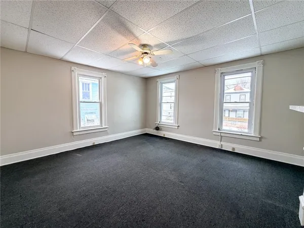 an empty room with a window and ceiling fan