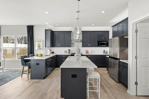 a large kitchen with a large counter top a sink stainless steel appliances and cabinets