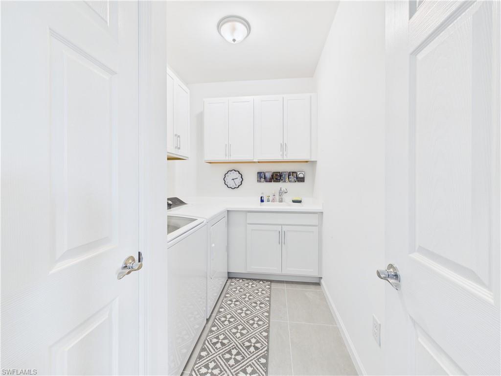 5683 Mayflower Way, Unit 908 Ave Maria, FL 34142 - Photo 22 of 37 Laundry area featuring light tile patterned flooring, washer and clothes dryer, and cabinet space