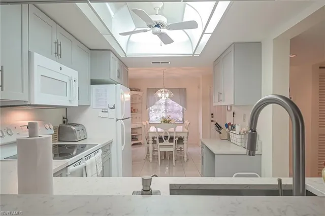 a kitchen with white cabinets and chandelier