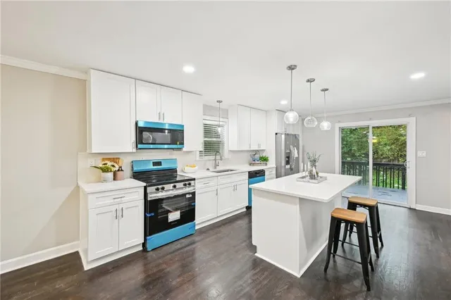 a kitchen with a sink a stove a refrigerator and white cabinets with wooden floor