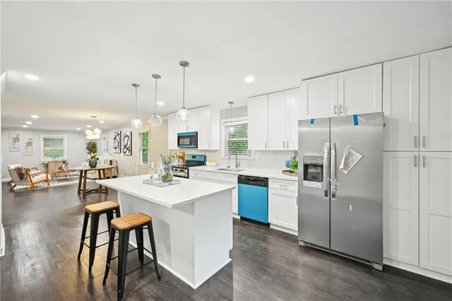 a kitchen with stainless steel appliances kitchen island a table chairs refrigerator and sink