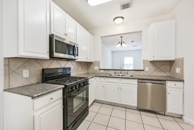 a kitchen with stainless steel appliances granite countertop a stove a sink and a microwave