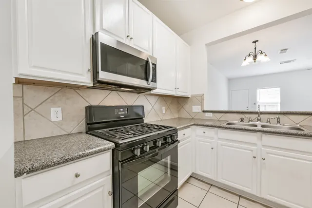 a kitchen with granite countertop white cabinets and appliances