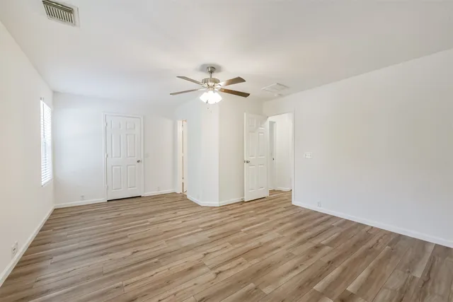 a view of an empty room with a ceiling fan window and a ceiling fan