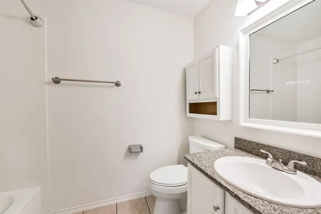 a bathroom with a granite countertop sink toilet and mirror