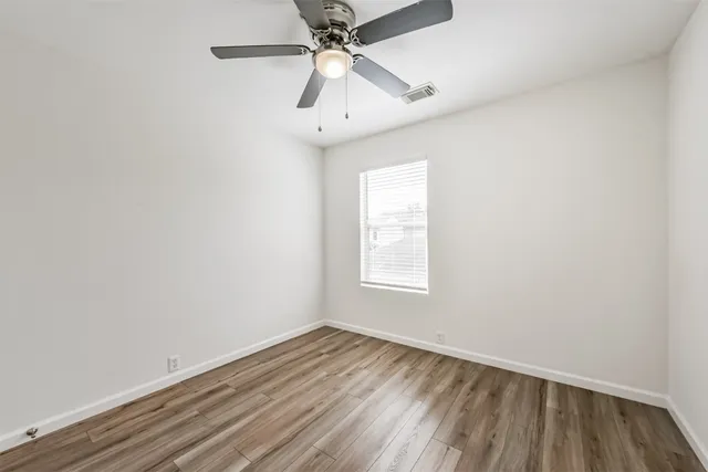an empty room with a window and ceiling fan