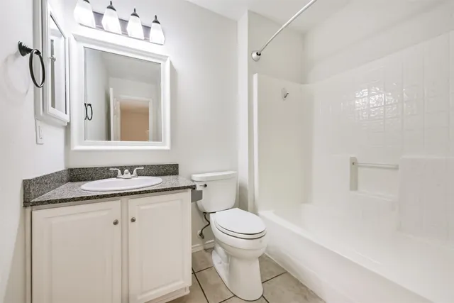 a bathroom with a granite countertop sink toilet and mirror