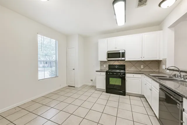 a kitchen with stainless steel appliances granite countertop a stove top oven a sink a counter space and cabinets