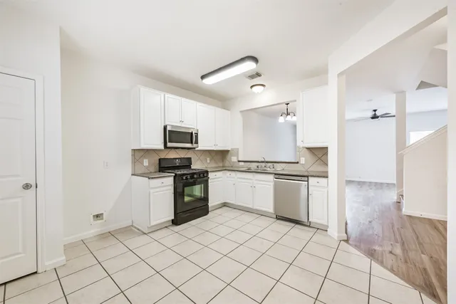 a kitchen with granite countertop a refrigerator and a stove top oven