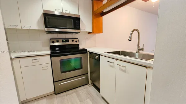 a kitchen with cabinets stainless steel appliances and wooden floor