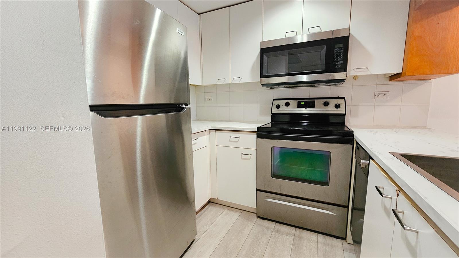 2801 Florida Avenue, Unit 441 Miami, FL 33133 - Photo 10 of 24 a kitchen with cabinets stainless steel appliances and wooden floor