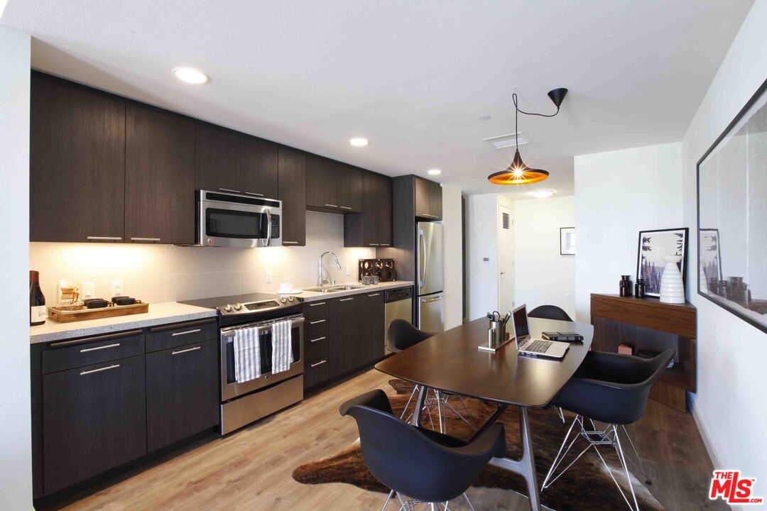 707 East Ocean Boulevard, Unit PH1615 Long Beach, CA 90802 - Photo 2 of 21 a kitchen with stainless steel appliances kitchen island granite countertop a sink a stove a kitchen island with chairs and wooden floor